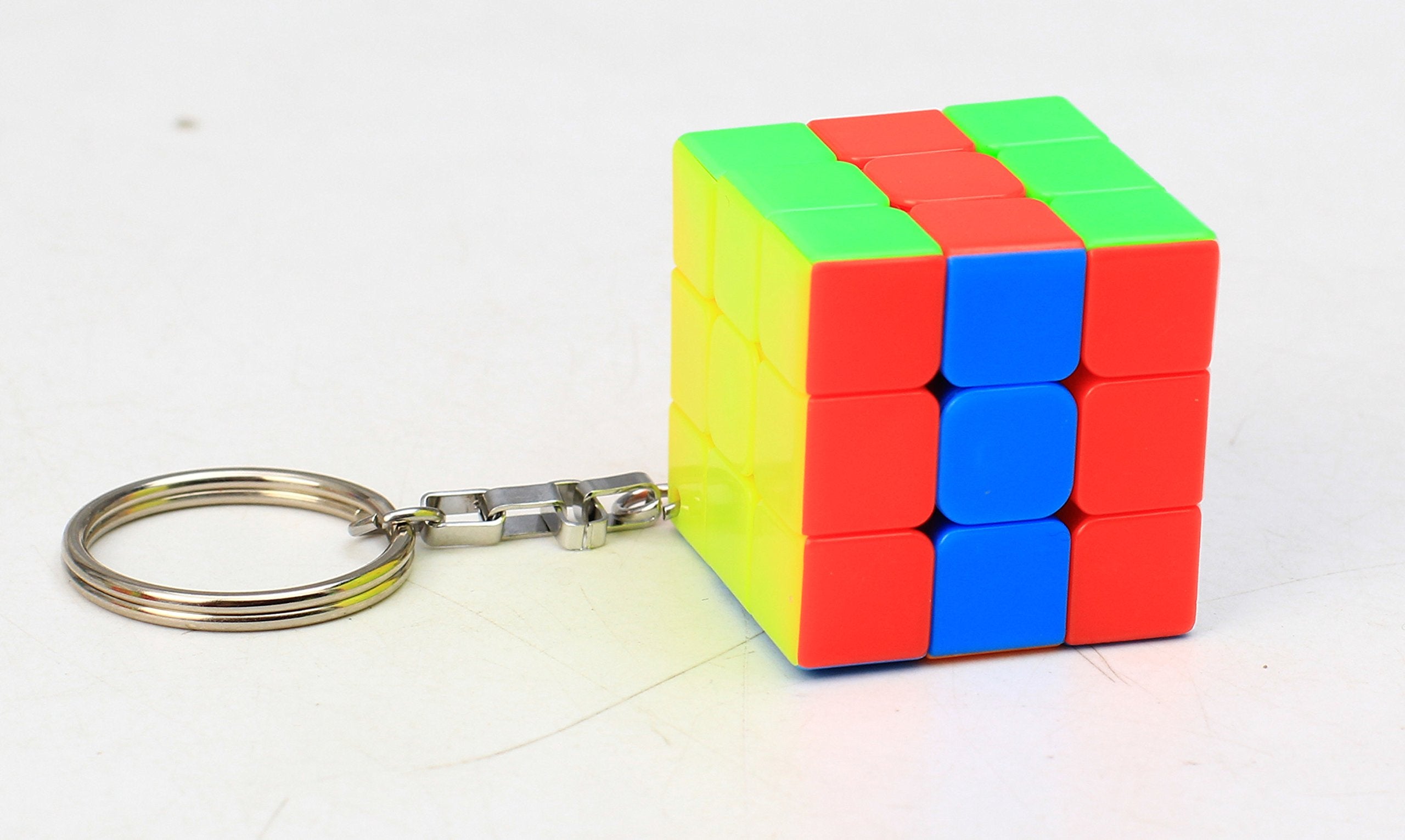 Rubiks Cube Keychain from a set of 10, featuring a mini 3x3 puzzle cube with red, blue, and white tiles. Ideal for travel and brain-boosting fun.